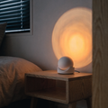 White Sunset Projection Lamp casting warm amber glow on a minimal bedroom wall